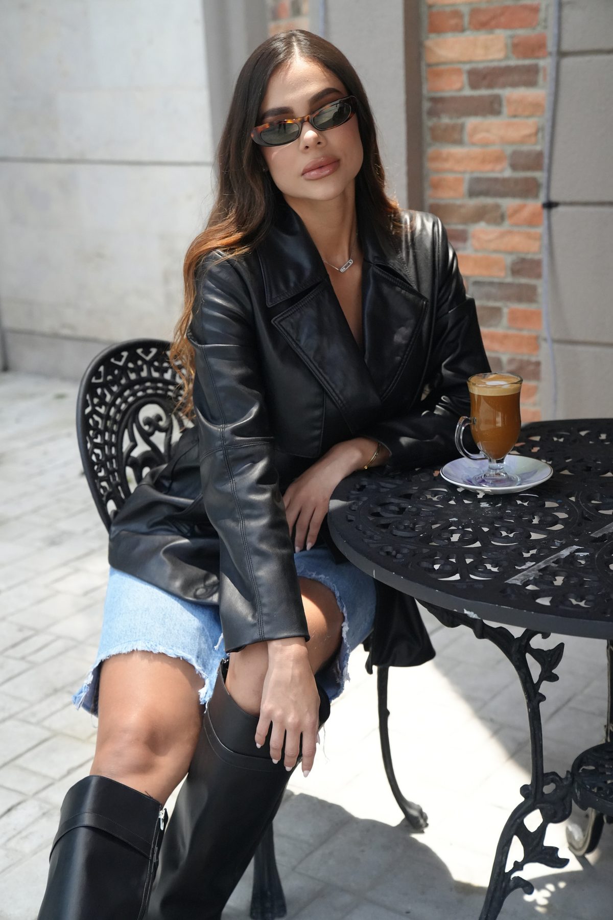 Tatiana Gaviria en chaqueta de cuero sentada en una mesa de café